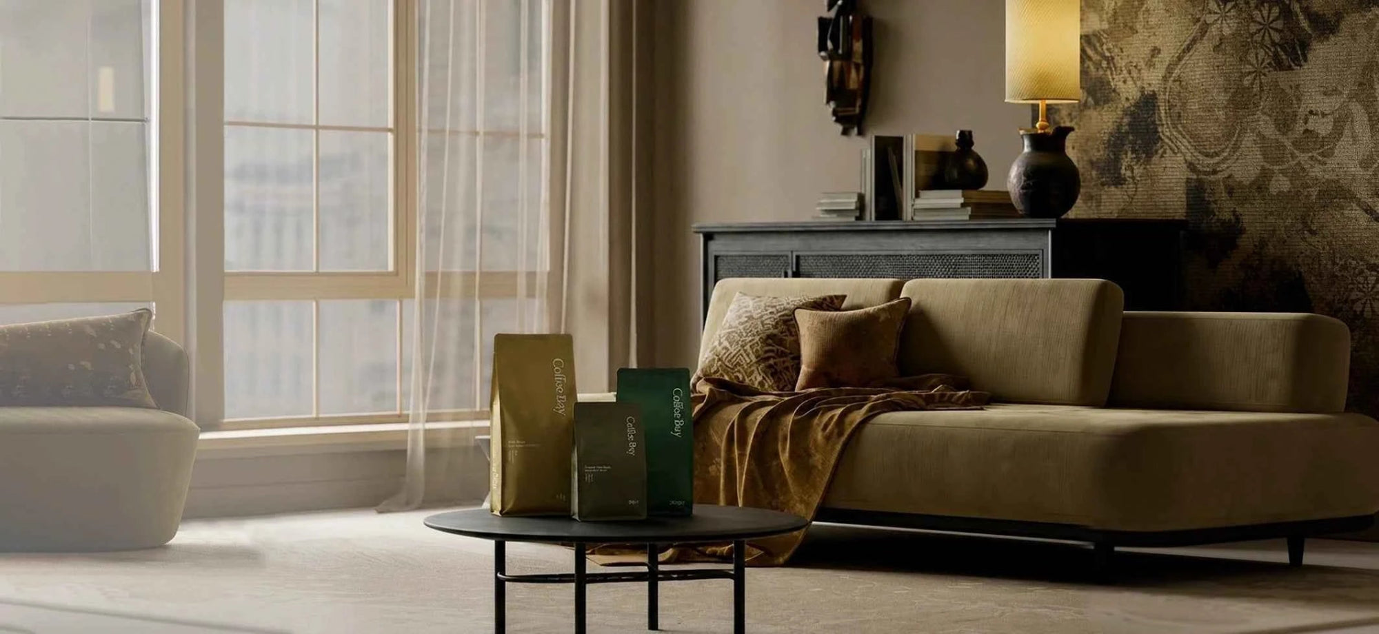 A modern beige fabric sofa in a styled living room setting, featuring a matching throw blanket, decorative pillows, a dark wood sideboard with a lamp, and a round coffee table in the foreground.